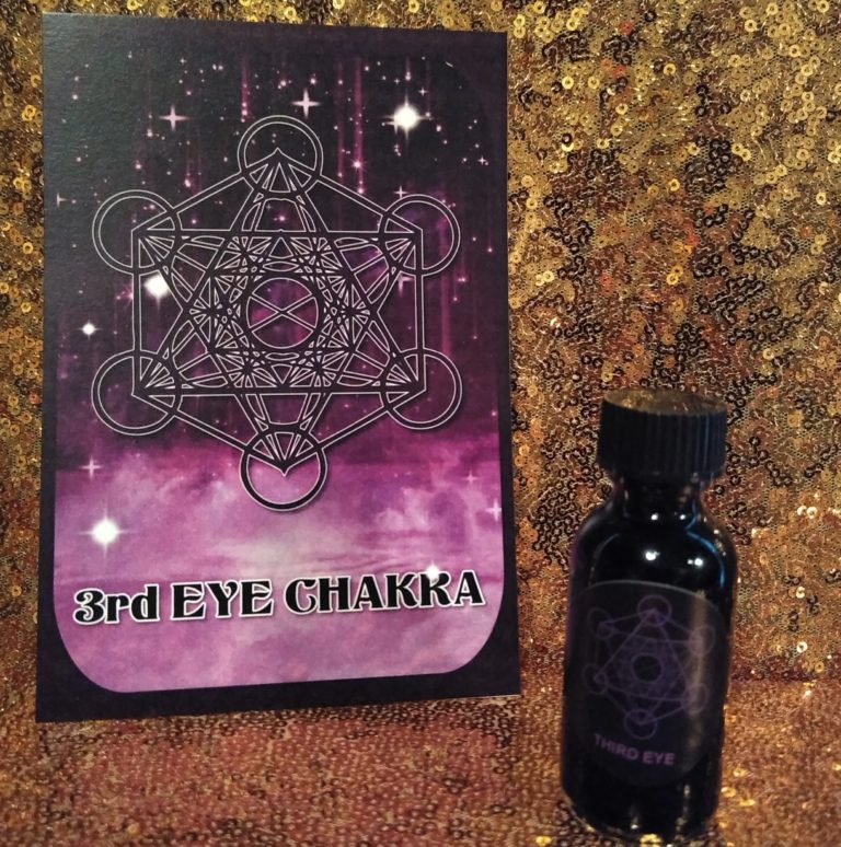 A bottle of eye chakra oil next to a book.