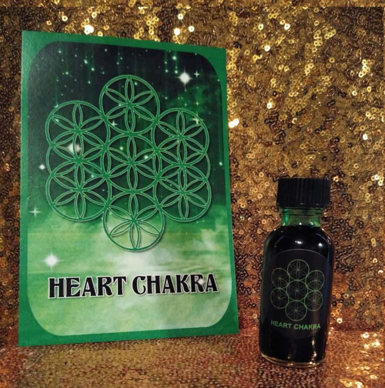 A bottle of heart chakra oil next to a book.