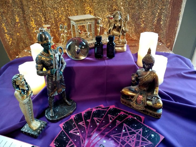 A purple table with candles and statues on it